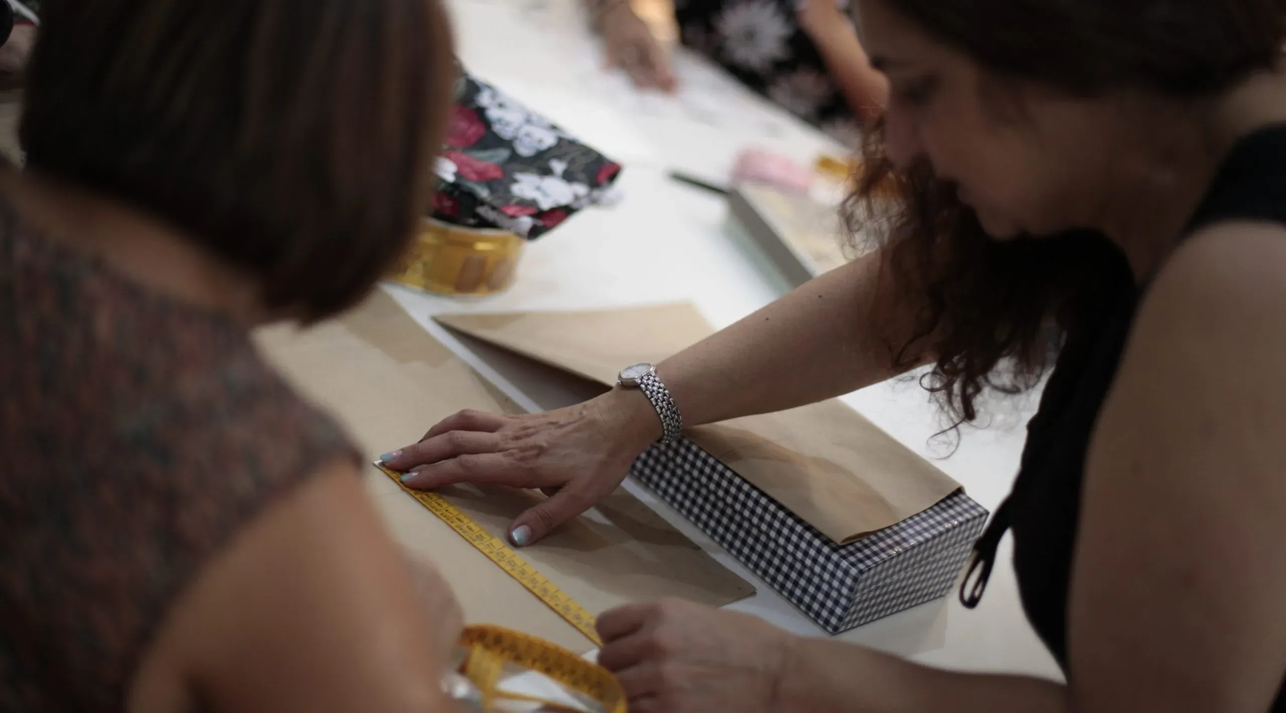 Alumnas midiendo y trabajando con telas en una clase de la Escuela Tresele
